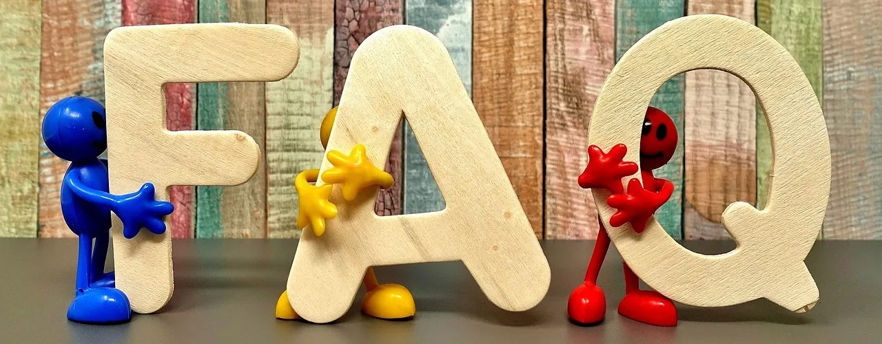3 petites figurines bleue, jaune et rouge tiennent des lettres FAQ en bois sur une table